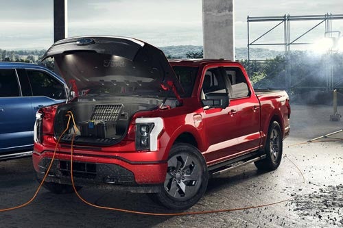 A 2024 Lightning® truck at construction site with power tools plugged into trunk